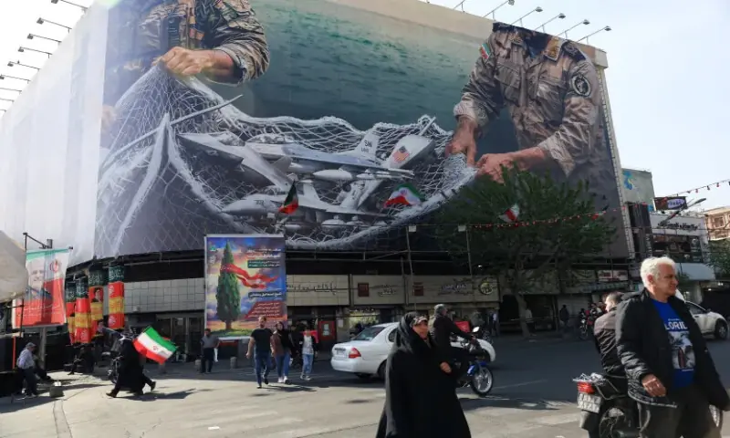 People walk near an anti-US billboard on a building in Tehran, Iran. &ndash; Reuters