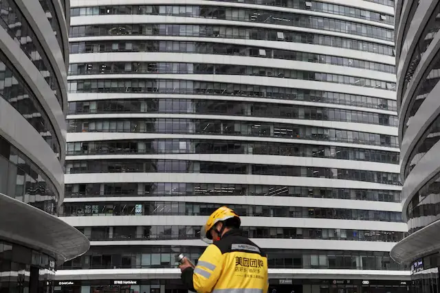 Meituan delivery worker walks among office towers in Beijing, China. &ndash; Reuters