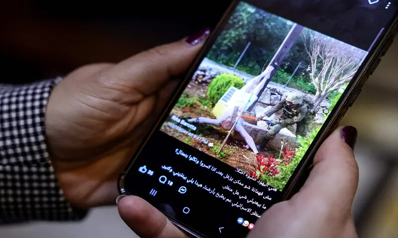 A woman checks a social media post on her mobile phone featuring an image that appears to show an Israeli soldier hitting a statue of Jesus Christ in the southern Lebanese Christian village of Debl, in Beirut on April 20, 2026. AFP