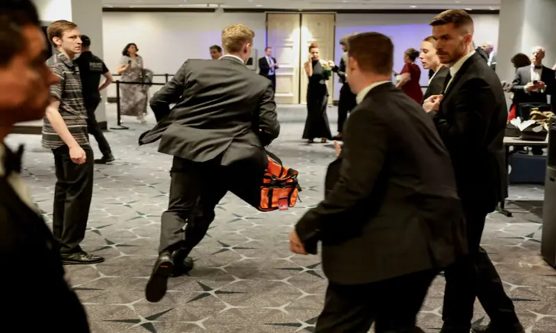 A security official runs with a bag as a shooter opens fire during the annual White House Correspondents' Association dinner in Washington. -- Reuters