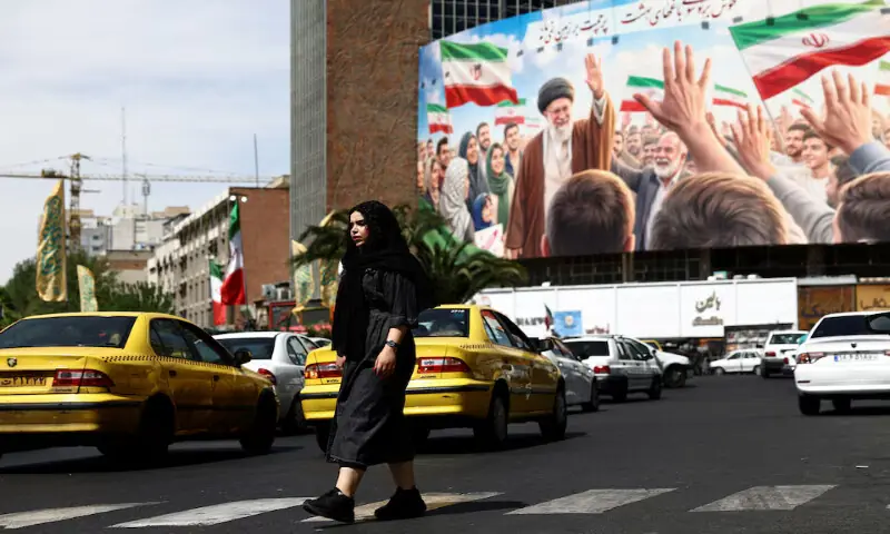 A woman walks past a billboard featuring an image of the late Supreme Leader Ayatollah Ali Khamenei on a building in Tehran, Iran. -- Reuters