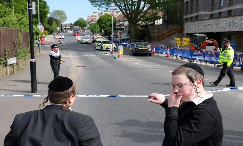 Orthodox Jews stand by a police cordon after a man was arrested following a stabbing incident in the Golders Green area in London. -- Reuters