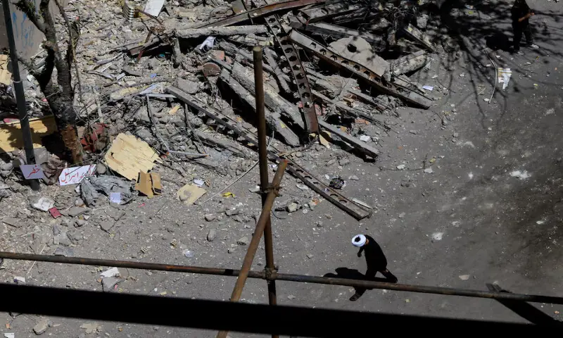 A cleric walks near a residential building damaged by a strike in Tehran, Iran. -- Reuters
