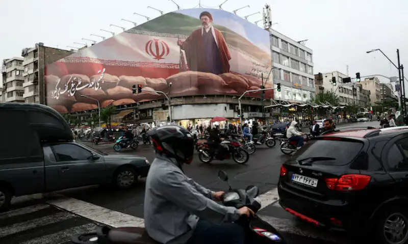 People ride motorcycles near a billboard featuring an image of Supreme Leader Mojtaba Khamenei in Tehran, Iran. -- Reuters
