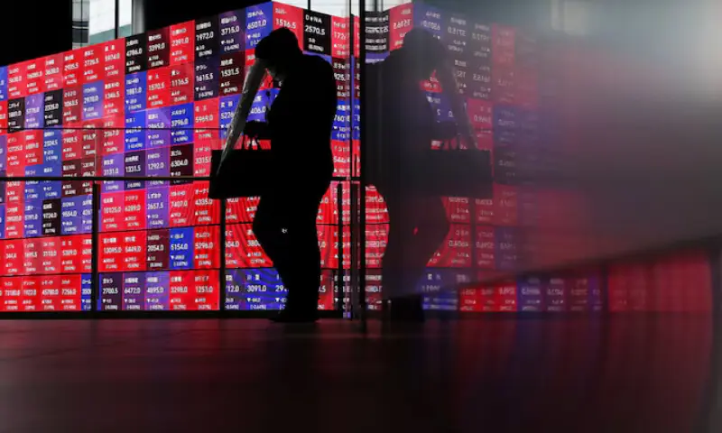 A man walks in front of an electronic screen displaying Japan's Nikkei stock prices quotation inside a conference hall in Tokyo, Japan. -- Reuters