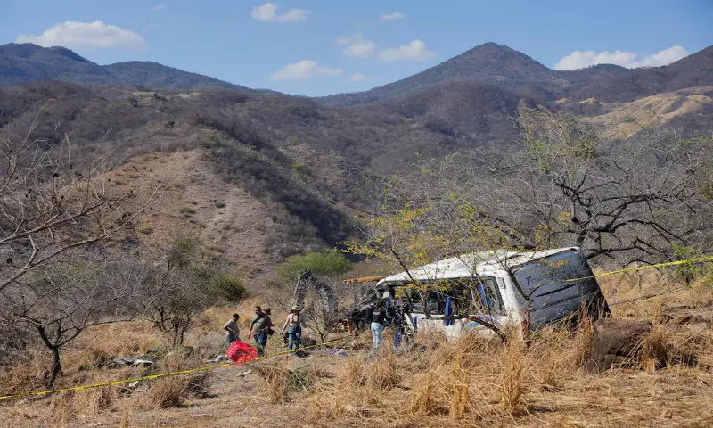 People and staff from the Nayarit Attorney General's office stand near the site where a tourist bus overturned near the town of Amatlan de Canas, in the western state of Nayarit, Mexico. -- Reuters