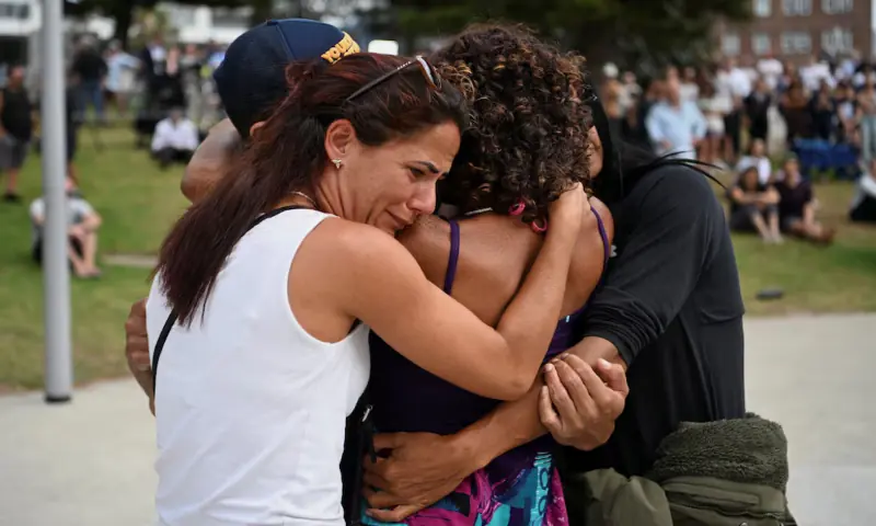 People embrace as they visit a makeshift memorial following the attack on Sydney's Bondi Beach, in Sydney, Australia. -- Reuters