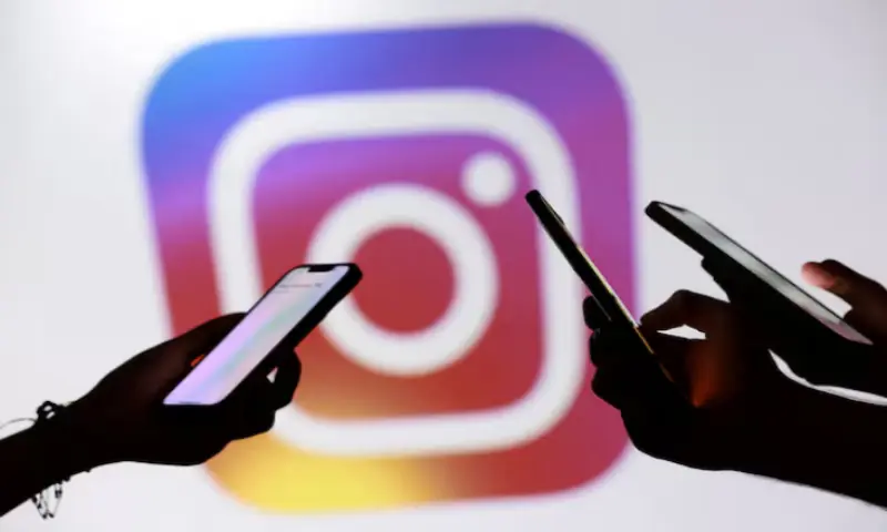 Teenagers pose for a photo while holding smartphones in front of a Facebook logo in this illustration. -- Reuters