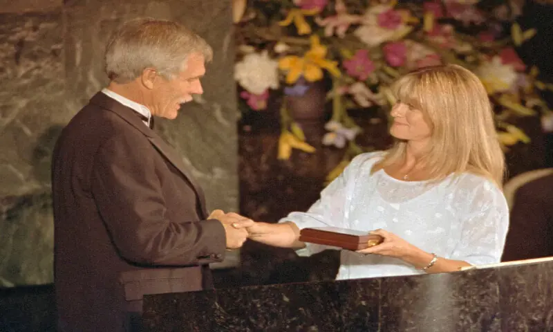 Singer Olivia Newton-John presents Ted Turner with the United Earth Inaugural prize for leadership in environmental communications in New York City on June 5, 1991. -- Reuters