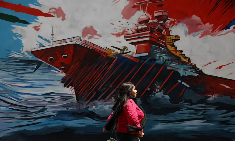 An Iranian woman walks next to a mural on a street in Tehran, Iran. -- Reuters