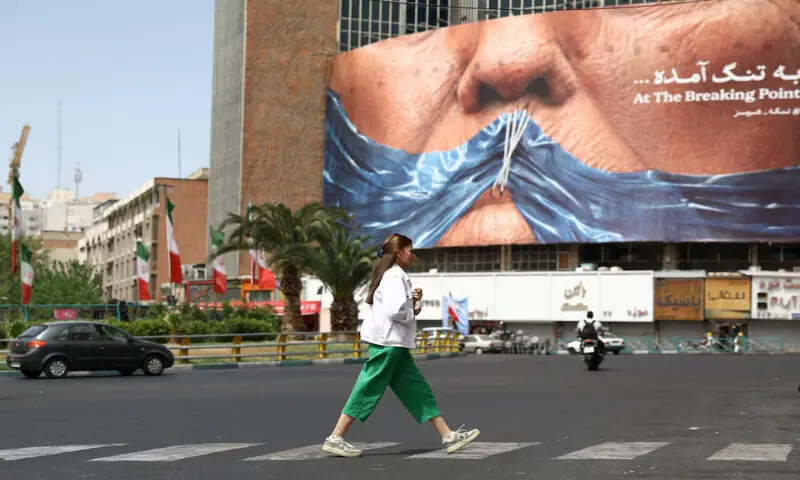 A woman walks past an anti-US billboard depicting US President Donald Trump and the Strait of Hormuz in Tehran. -- Reuters