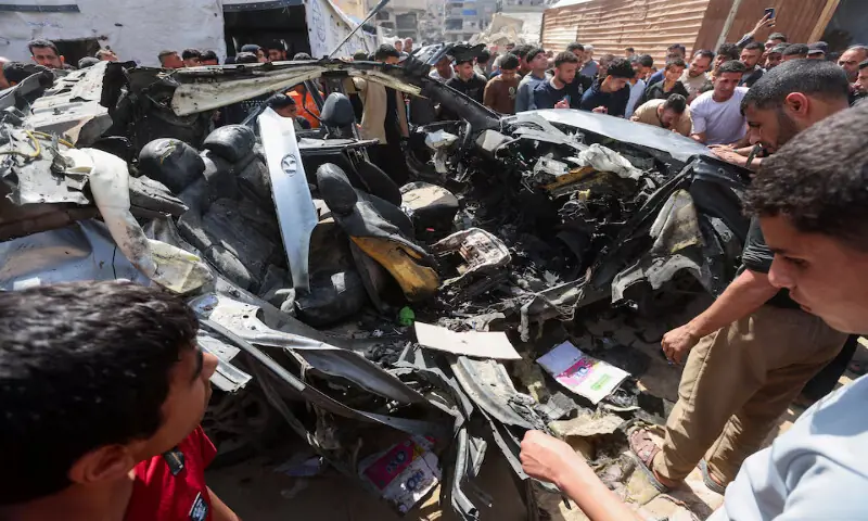 Palestinians inspect the site of an Israeli strike on a car in Khan Younis, in the southern Gaza Strip. -- Reuters