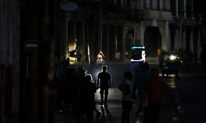 People walk on a street during a blackout in Havana on May 13, 2026. AFP