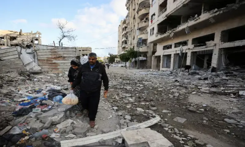 Palestinians walk at the site of an Israeli air strike on a residential building in Gaza City. -- Reuters