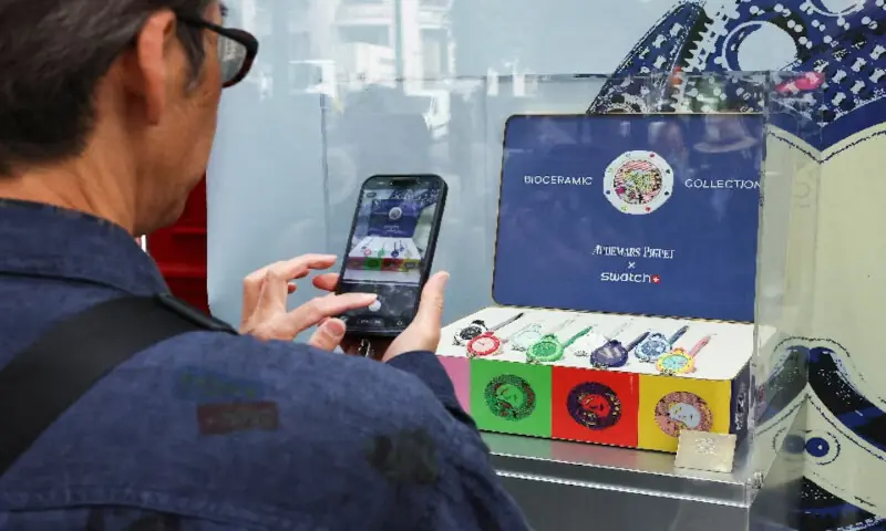 A man takes a photo through the window of the Swiss watch store Swatch to capture the new limited-edition 'Royal Pop' watches in Paris, France. -- Reuters