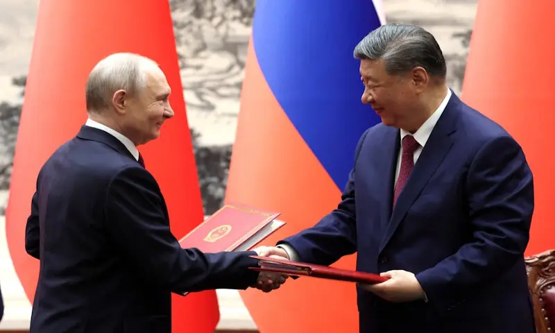 Russian President Vladimir Putin and Chinese President Xi Jinping exchange documents at a ceremony in Beijing on Wednesday. -- Reuters