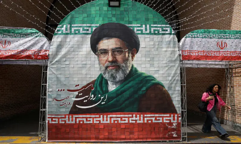 A woman walks next to a banner with a picture of Iran's new Supreme Leader Mojtaba Khamenei in Tehran, Iran. -- Reuters