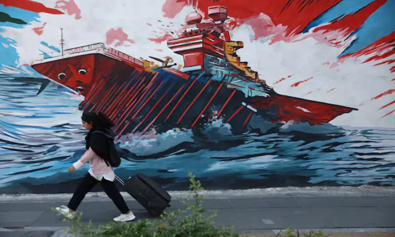An Iranian woman walks next to a mural on a street in Tehran, Iran. -- Reuters