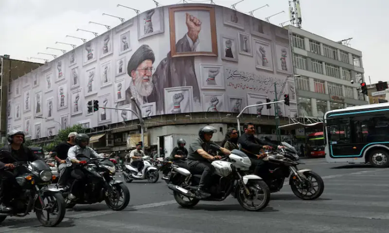 People ride motorcycles near a billboard with an image of the late Iranian Supreme Leader Ayatollah Ali Khamenei in Tehran, Iran. -- Reuters