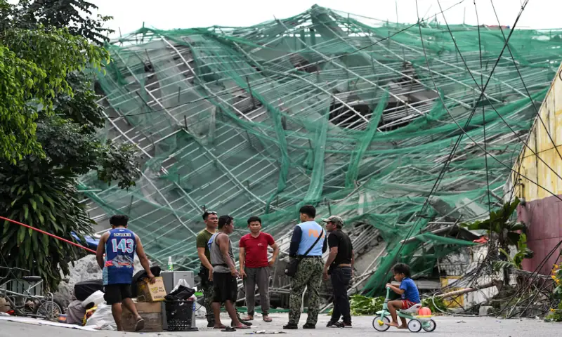 Policemen talk to workers as they leave their site accommodation at the foot of the nine-storey building that collapsed under construction in Balibago, Angeles City, Pampanga, Philippines. -- Reuters