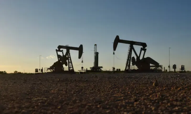 Pump jacks operate in front of a drilling rig in an oil field in Midland, Texas US. -- Reuters