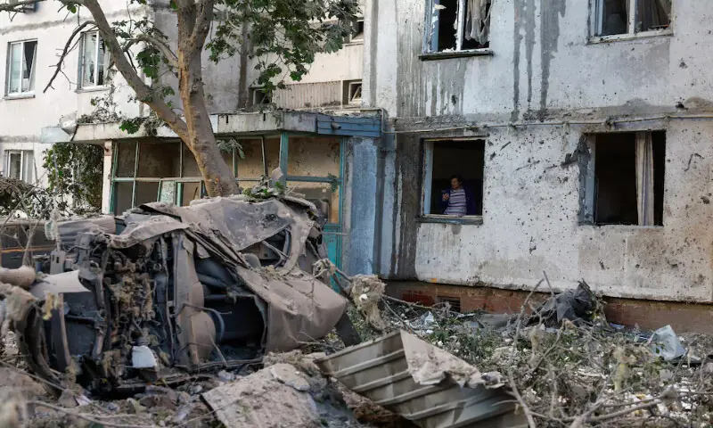 A woman inspects a building damaged during Russian missile and drone strikes in Kyiv, Ukraine, on Tuesday. -- Reuters