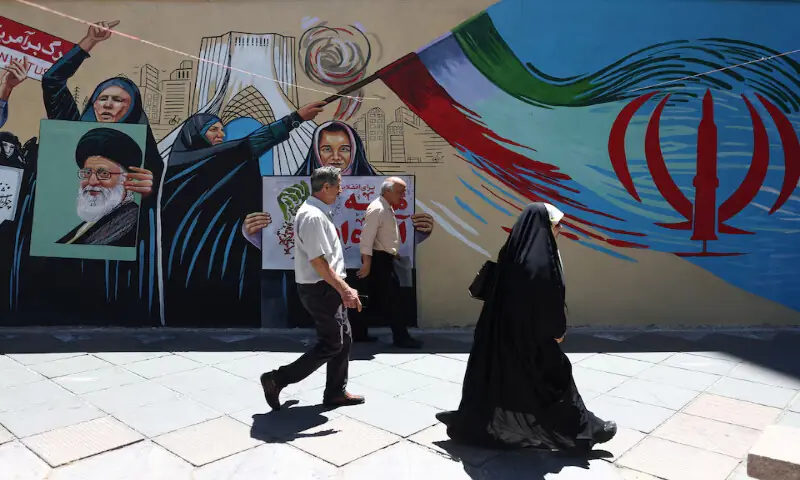 People walk on a street near a mural featuring an image of the late Supreme Leader Ayatollah Ali Khamenei in Tehran, Iran. -- Reuters