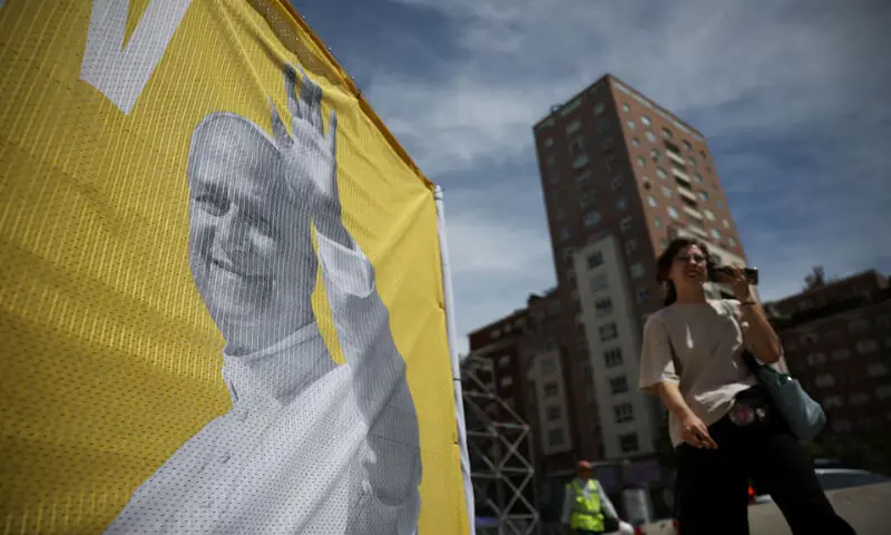 A person walks past a banner announcing the visit of Pope Leo XIV outside the Santiago Bernabeu Stadium in Madrid, Spain. -- Reuters