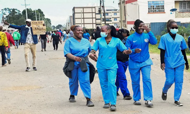 Women dressed in scrubs walk along the street as demonstrators participate during a protest against a US-backed Ebola quarantine plan on the establishment of a 50-bed facility at a Kenyan air force base that was intended to host Americans exposed to Ebola, in Nanyuki town, in Laikipia County, Kenya. -- Reuters