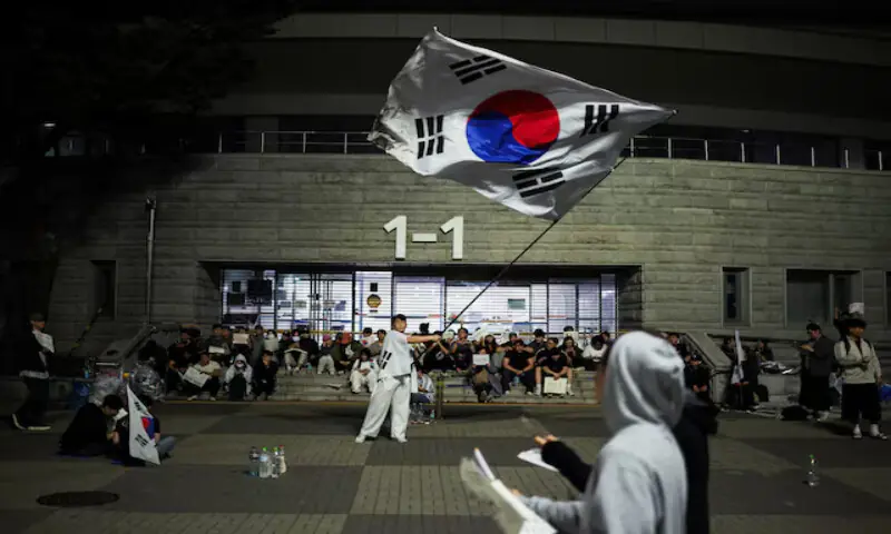 A demonstrator waves a large South Korean flag as people surround a vote-counting centre in Seoul, South Korea. -- Reuters