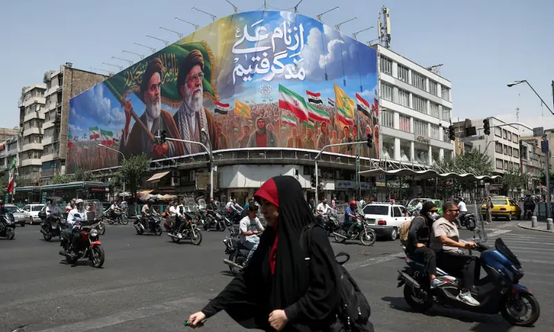 People ride past a billboard depicting the late leader of the Islamic Revolution, Ayatollah Ruhollah Khomeini, and the late Iran's Supreme Leader, Ayatollah Ali Khamenei, on a street in Tehran, Iran. -- Reuters