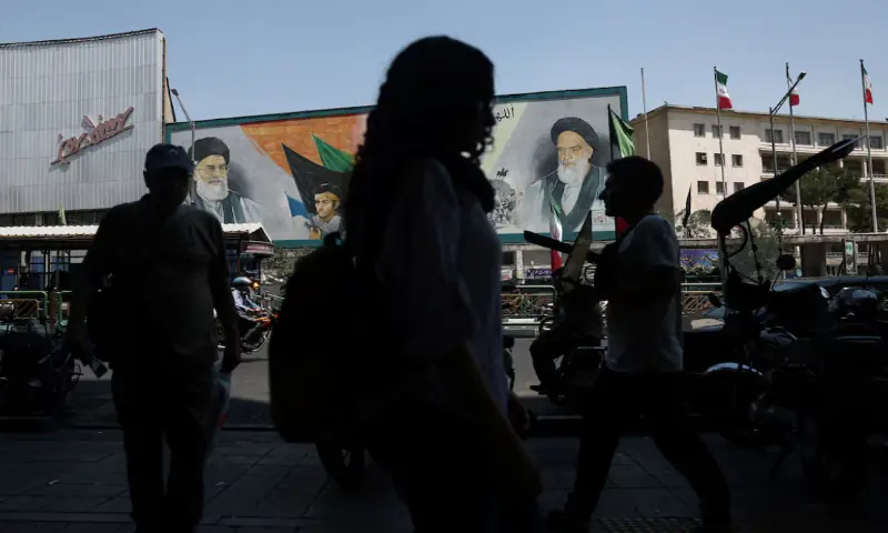 People walk past a mural depicting the late leader of the Islamic Revolution, Ayatollah Ruhollah Khomeini, and the late Iran's Supreme Leader Ayatollah Ali Khamenei, on a street in Tehran, Iran. -- Reuters