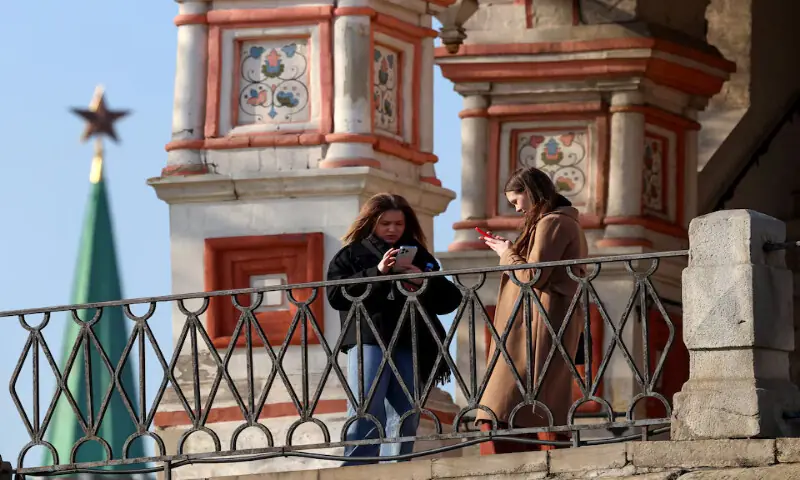 People use mobile phones while standing outside St. Basil's Cathedral in central Moscow, Russia. -- Reuters