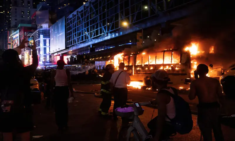 People stand near a shuttle bus outside the Port Authority Bus Terminal after it was set on fire during celebrations of the New York Knicks&rsquo; victory over the San Antonio Spurs in New York City, US. -- Reuters