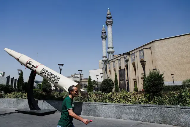 A man walks next to a symbolic mock-up of an Iranian missile, on a street in Tehran, Iran. -- Reuters