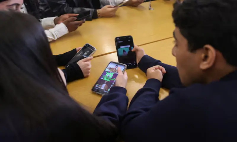 Students from Ricards Lodge and Rutlish High Schools in Wimbledon look at their mobile phones during an interview and discussion with Reuters about their thoughts on a social media ban for under 16s, in London, Britain. -- Reuters