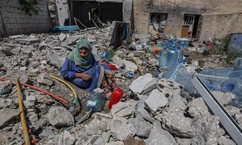 Khadija Amara, whom local residents said had not left her home, fills a jerrycan with water as she sits among the rubble of a house, which was damaged by an Israeli strike, in Qlaileh in the Tyre district, southern Lebanon. -- Reuters