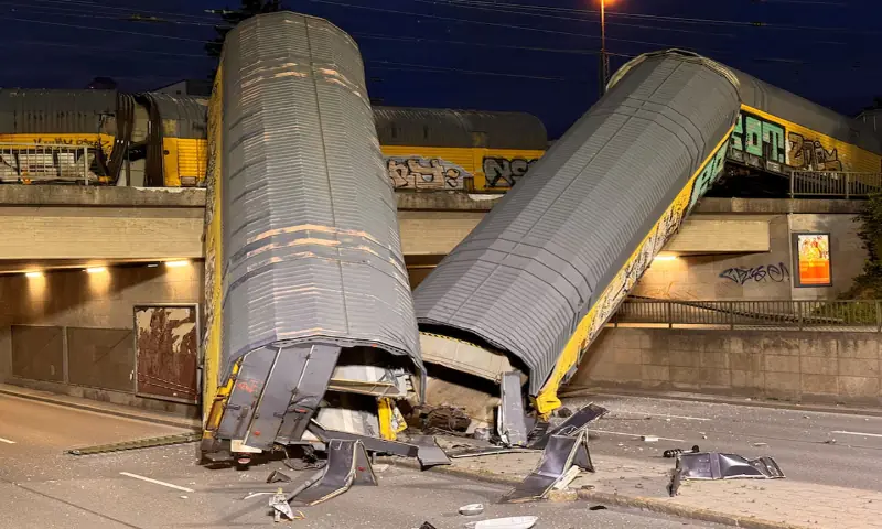 Two cars of a freight train which derailed after a collision, fell off a bridge and lay on a road in Munich, Germany. -- Reuters Two cars of a freight train which derailed after a collision, fell off a bridge and lay on a road in Munich, Germany. -- Reuters