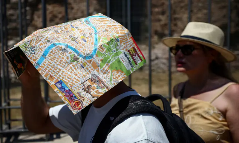 A tourist uses a map of Rome to shield their face from the sun beside the base of the Temple of Venus and Roma, opposite the Colosseum, during a heatwave in Rome, Italy. -- Reuters