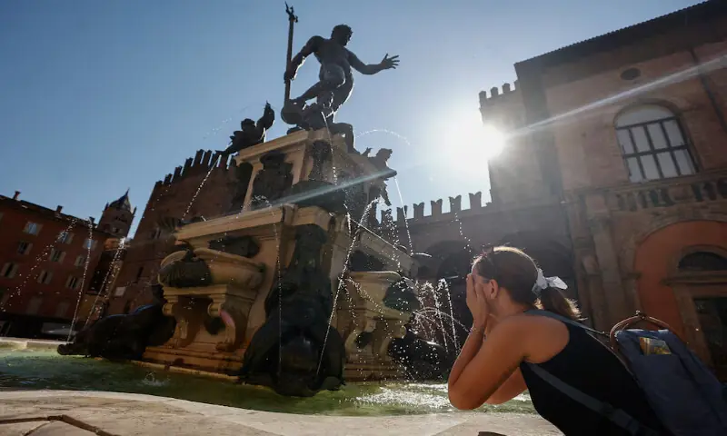A woman splashes water on her face at the Fountain of Neptune during hot weather in Bologna, Italy. -- Reuters