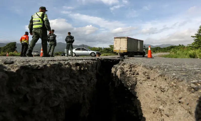 Members of the Bolivarian National Guard of Venezuela stand on a road cracked after two strong earthquakes in Moron, Venezuela. -- Reuters