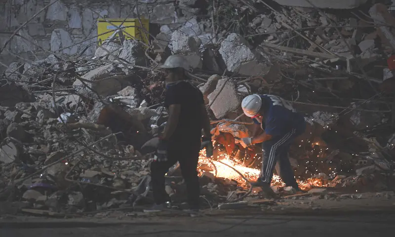 A rescuer cuts the steel bars of a collapsed building with an angle grinder in Caracas on June 25, 2026, following deadly earthquakes. AFP