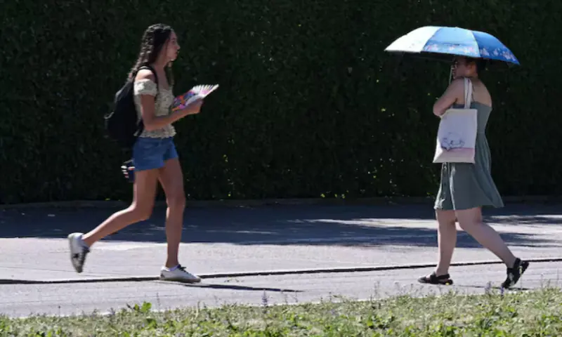People use umbrellas and fans to protect themselves from high temperatures in Munich, Germany. -- Reuters
