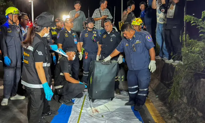 Rescue workers and forensic technicians with a suitcase, in which police later found the body of a 17-year-old Thai girl, for examination, after it was recovered from a grassy area near a railway track in Pattaya City, Thailand. -- Reuters