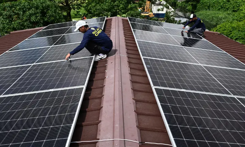 Workers install solar panels on the roof of a house in Kawit, Philippines. -- Reuters