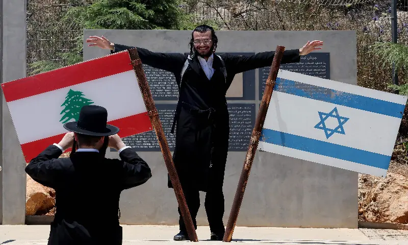 An Ultra-Orthodox Jewish men poses beside Israeli and Lebanese flags at a memorial site on the border with Lebanon in northern Israel, on July 1, 2026. AFP