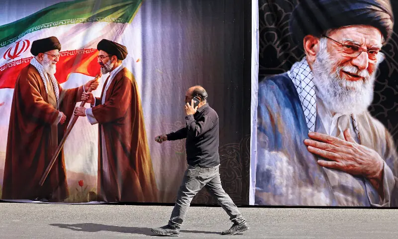 A man walks past a billboard featuring the images of Iran's slain supreme leader Ali Khamenei and his son, the current supreme leader Mojtaba Khamenei, along the street in Tehran on July 3, 2026. AFP