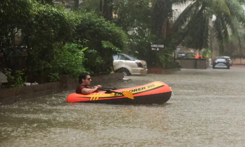 A man rows an inflatable raft inside a waterlogged building society in Mumbai, India. -- Reuters