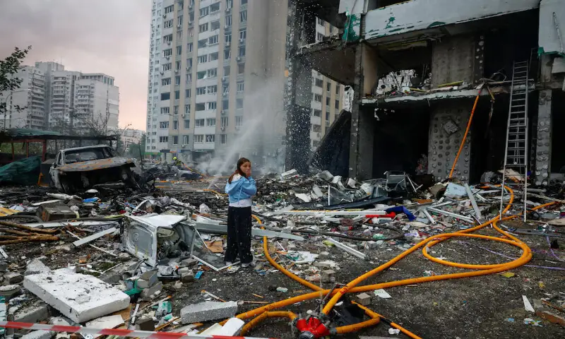 A resident reacts while she waits for rescuers who are searching for her relative inside an apartment building which was hit during Russian missile and drone strikes in Kyiv, Ukraine, on Monday. -- Reuters