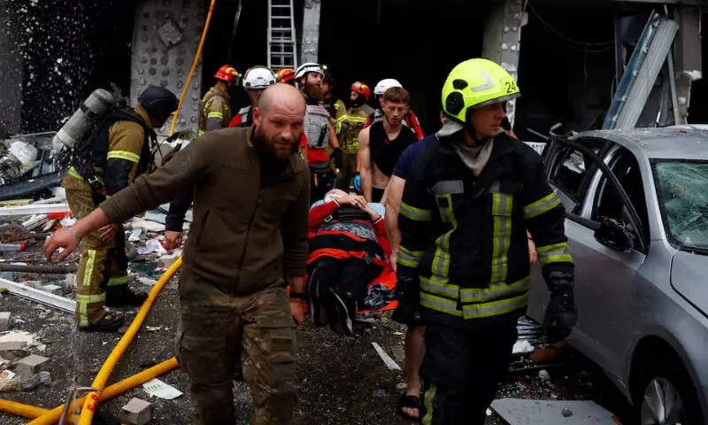 Rescuers carry an injured resident at the site of an apartment building which was heavily damaged during Russian missile and drone strikes in Kyiv, Ukraine, on Monday. -- Reuters